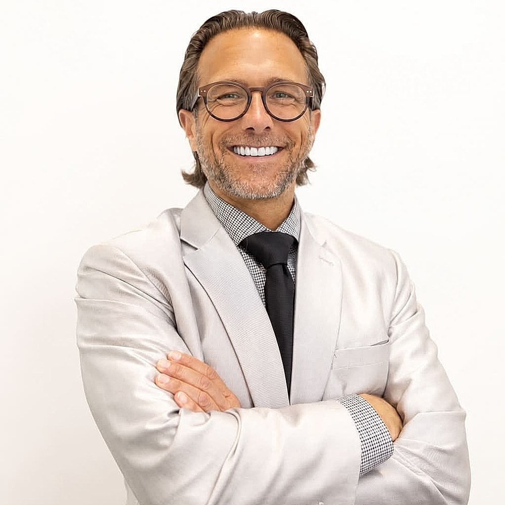 Smiling man in a suit with crossed arms.